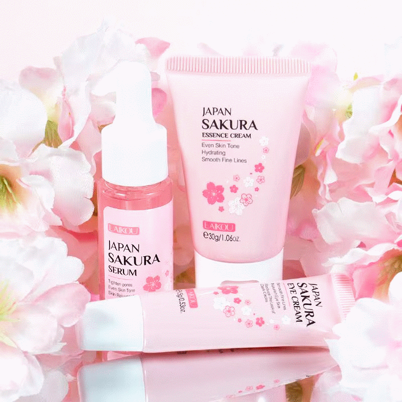 Lensemble de soins du visage Laikou Sakura de Jay Cosmetic est présenté sur une surface rose avec son Nettoyant Visage Sakura, son toner, sa crème, son sérum à la niacinamide et son baume à lèvres dans un emballage sur le thème des fleurs de cerisier. Une boîte ouverte révélant un motif floral se trouve au milieu de pétales de fleurs de cerisier dispersés.
